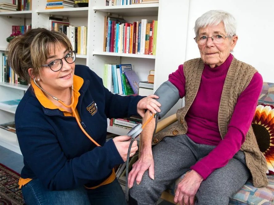 Eine Mitarbeiterin des Pflegedienstes Wunsiedel führt bei einer älteren Dame eine Blutdruckmessung durch.